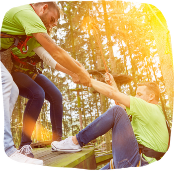 Exercice de cohésion d'équipe : deux collègues aident un participant à monter sur une plateforme lors d'un team building