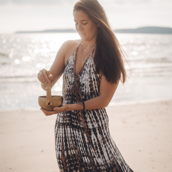 Vannaly faisant résonner un bol tibétain sur la plage lors d'un coaching hypersensible